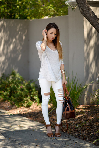 Модный лук: белая футболка с длинным рукавом, белые рваные джинсы скинни, коричневые кожаные босоножки на каблуке, черная кожаная большая сумка