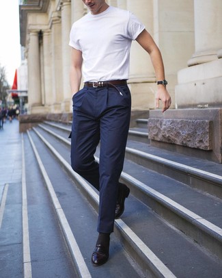С чем носить темно-синие брюки карго в жару: Если ты делаешь ставку на удобство и практичность, белая футболка с круглым вырезом и темно-синие брюки карго — классный выбор для привлекательного мужского образа на каждый день. Любишь экспериментировать? Дополни образ черными кожаными лоферами.