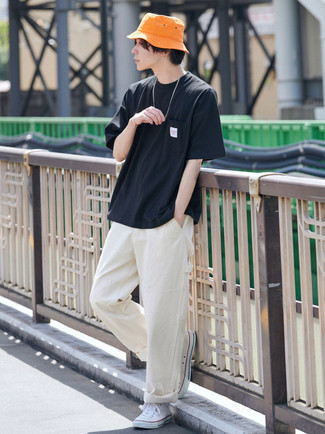 Модный лук: черная футболка с круглым вырезом, бежевые брюки чинос, белые высокие кеды из плотной ткани, оранжевая панама