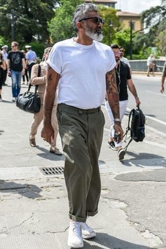 С чем носить оливковые брюки чинос за 50 лет: Белая футболка с круглым вырезом и оливковые брюки чинос выигрышно вписываются в гардероб самых избирательных джентльменов. Дополнив ансамбль белыми кроссовками, ты привнесешь в него свежие нотки.