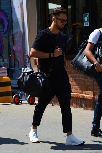 Модный лук: черная футболка с круглым вырезом, черные брюки чинос, белые кроссовки, черная кожаная дорожная сумка