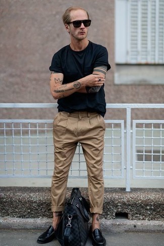 Модный мужской лук: темно-синяя футболка с круглым вырезом, светло-коричневые брюки чинос, черные кожаные лоферы, темно-серая большая сумка из плотной ткани