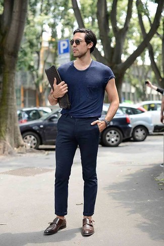 Модный лук: темно-синяя футболка с круглым вырезом, темно-синие брюки чинос, коричневые кожаные монки с двумя ремешками, черный кожаный плетеный мужской клатч