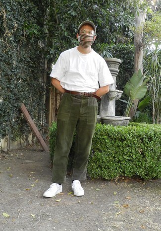 С чем носить оливковые вельветовые брюки чинос в 30 лет лето: Белая футболка с круглым вырезом и оливковые вельветовые брюки чинос — превосходный вариант для расслабленного, но стильного мужского образа. Белые низкие кеды из плотной ткани — прекрасный выбор, чтобы завершить лук. Не стоит забывать о таком образе, особенно в жаркий день.