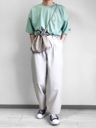 Модный лук: мятная футболка с круглым вырезом, серые брюки чинос, темно-сине-белые низкие кеды из плотной ткани, серая сумка почтальона из плотной ткани