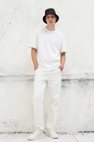 Модный лук: белая футболка с круглым вырезом, белые брюки чинос, белые кожаные низкие кеды, черная панама