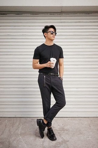 С чем носить темно-серые брюки чинос в жару: Черная футболка с круглым вырезом и темно-серые брюки чинос — замечательная идея для простого, но модного мужского лука. Сделать лук чуть строже помогут черные кожаные туфли дерби.