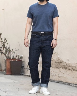 Как носить джинсы с высокими кедами мужчине в жару: Темно-синяя футболка с круглым вырезом будет смотреться стильно в сочетании с джинсами. Ты сможешь легко приспособить такой образ к повседневным условиям городской жизни, дополнив его высокими кедами.