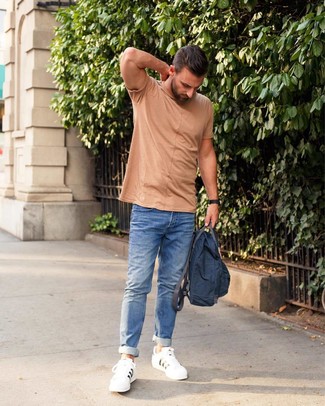 Модный лук: светло-коричневая футболка с круглым вырезом, синие джинсы, белые кожаные низкие кеды, темно-синий рюкзак из плотной ткани