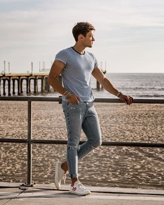 С чем носить голубые джинсы в 20 лет мужчине в спортивном стиле: Если этот день тебе предстоит провести в движении, сочетание бело-темно-синей футболки с круглым вырезом в горизонтальную полоску и голубых джинсов поможет составить удобный образ в непринужденном стиле. Бежевые низкие кеды из плотной ткани с принтом великолепно впишутся в образ.