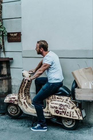 Модный мужской лук: голубая футболка с круглым вырезом, темно-синие джинсы, темно-сине-белые низкие кеды из плотной ткани, светло-коричневые кожаные часы