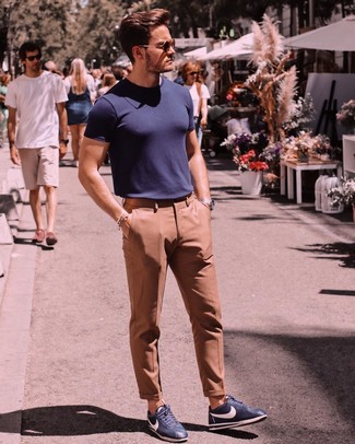 С чем носить светло-коричневые классические брюки в 30 лет мужчине лето в стиле смарт-кэжуал: Любителям стиля smart casual придется по вкусу сочетание темно-синей футболки с круглым вырезом и светло-коричневых классических брюк. Этот образ стильно дополнят темно-синие кожаные низкие кеды. Нечего и говорить, подобное сочетание будет великолепным выбором для жаркой летней погоды.