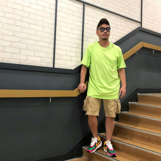 Модный мужской лук: зелено-желтая футболка с круглым вырезом, светло-коричневые шорты, разноцветные кроссовки, коричневая бейсболка