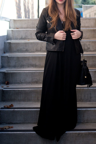 Модный лук: черная кожаная косуха, черное платье-макси, черная замшевая сумка-мешок, золотая подвеска