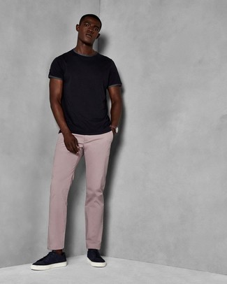 С чем носить розовые брюки чинос в жару: Черная футболка с круглым вырезом и розовые брюки чинос — неотъемлемые вещи в арсенале стильного молодого человека. Что касается обуви, темно-синие замшевые низкие кеды — самый приемлимый вариант.