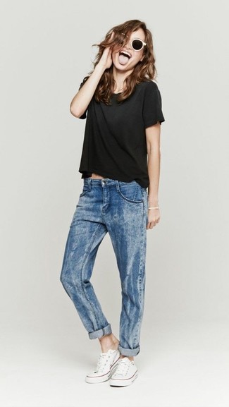 Модный лук: черная футболка с круглым вырезом, синие джинсы-бойфренды, белые низкие кеды из плотной ткани, бело-черные солнцезащитные очки