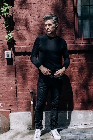 С чем носить черные кожаные джинсы за 50 лет мужчине: Сочетание черного свитера с круглым вырезом и черных кожаных джинсов в мужском образе поможет создать ощущение "элегантной свободы". Пара белых низких кед легко вписывается в этот образ.