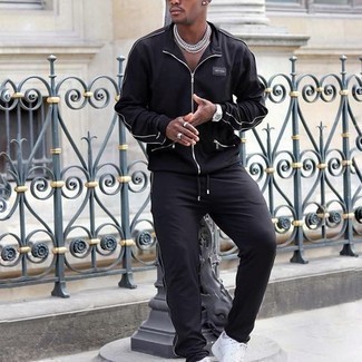 Модный лук: черный спортивный костюм, белые низкие кеды из плотной ткани, серебряные часы, белые носки