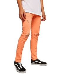 Оранжевые рваные зауженные джинсы